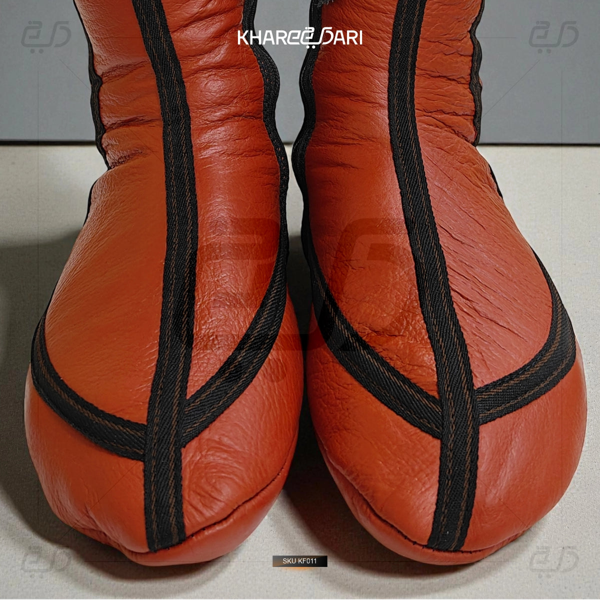 Pair of orange leather shoes with black straps on a light gray background Red