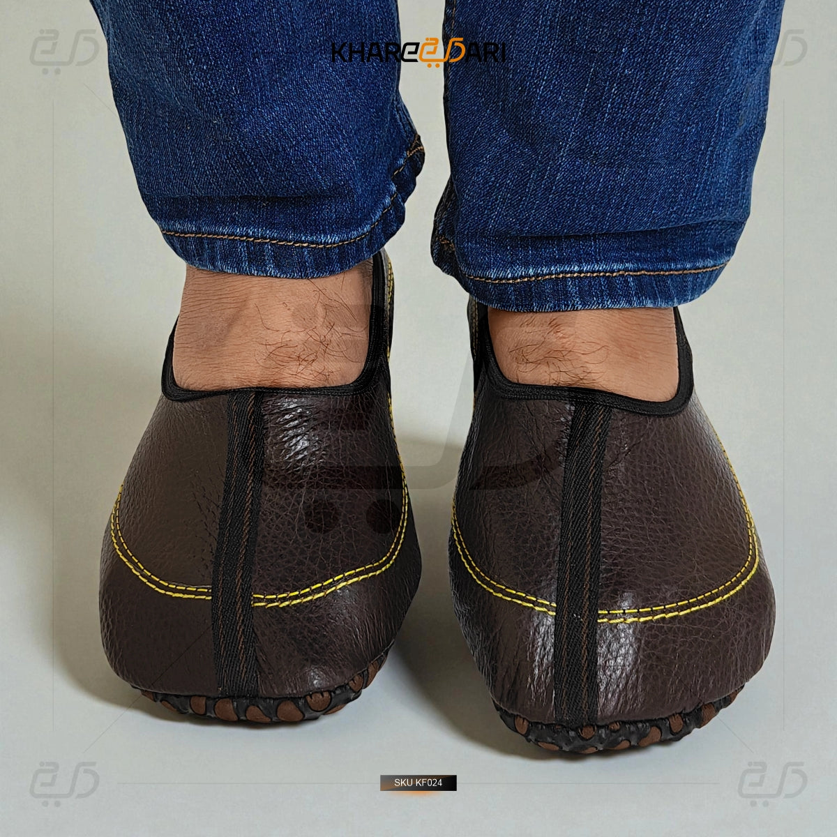 Brown leather shoes with yellow stitching worn with blue jeans on a light background Dark Brown