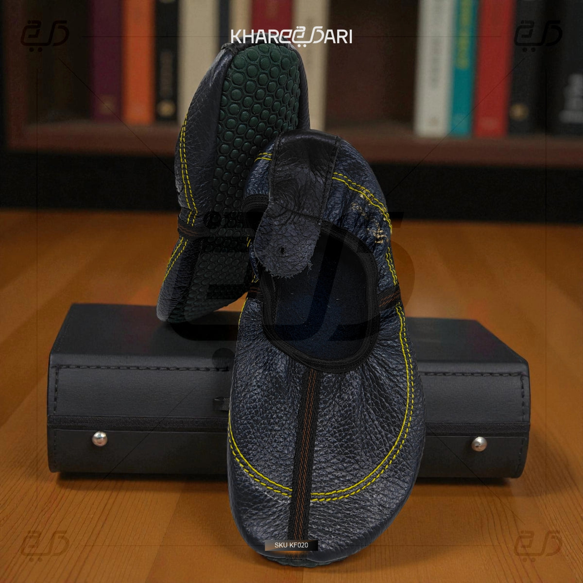 Pair of blue slippers with yellow accents on a black box against a blurred bookshelf background. Purple