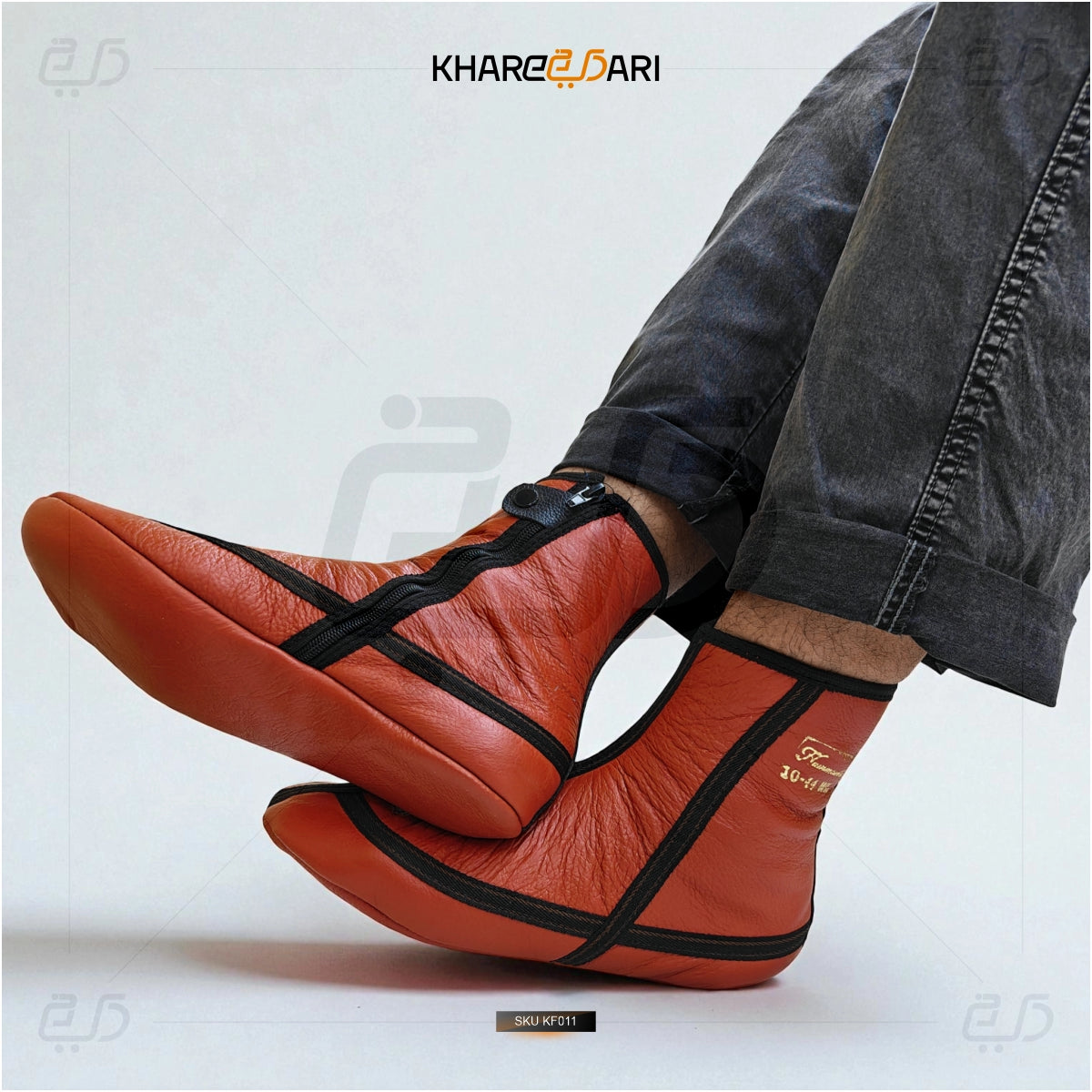 Red slip-on shoes with black straps worn by a person, on a light gray background with 'Khareebari' branding. Red