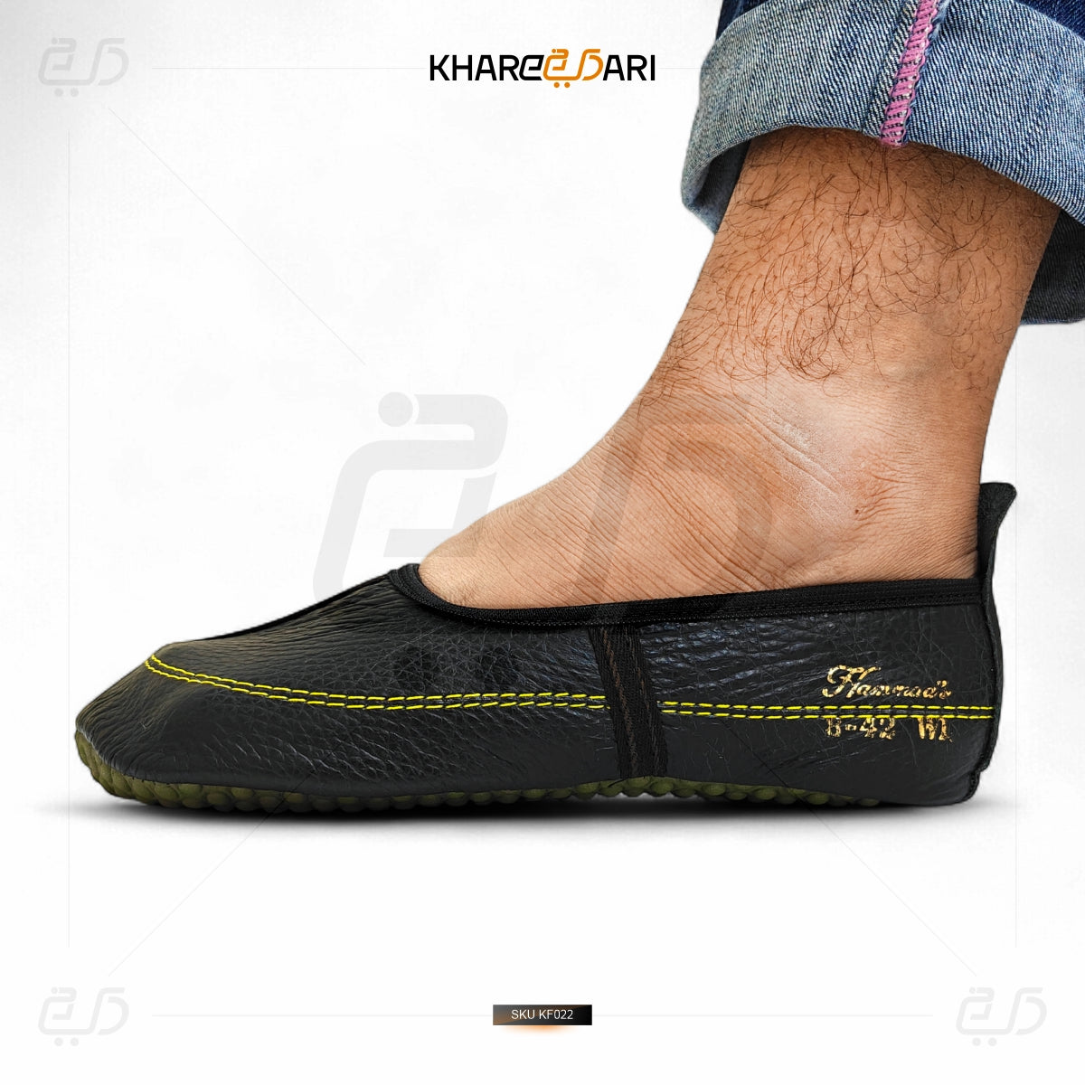 Black slip-on shoe with yellow stitching on a white background, featuring the brand 'Khareebari'. Black