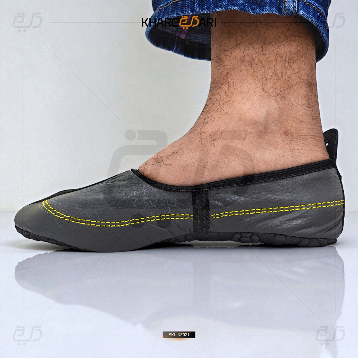 Gray slip-on shoe with yellow stitching worn by a person on a white background Grey
